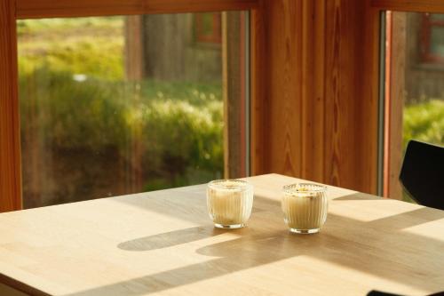 two glasses of milk sitting on top of a table at Múlafossur Cottages by famous waterfall in Gásadalur in Gásadalur