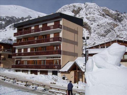 un homme debout devant un bâtiment dans la neige dans l'établissement Appartement cosy 4 pers avec mezzanine, balcon exposé sud, WiFi, centre Valloire, près des remontées - FR-1-263-27, à Valloire