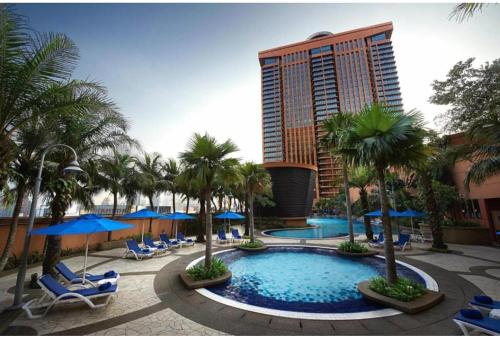 a resort with a pool and palm trees and a building at Kl Continew Suite At Times Square in Kuala Lumpur