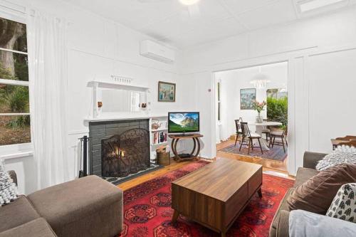 ein Wohnzimmer mit Sofa und Kamin in der Unterkunft Historic Corinda Cottage in Bundanoon