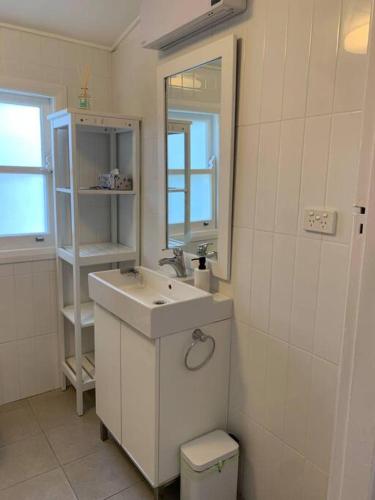 a bathroom with a sink and a mirror and a toilet at Historic Corinda Cottage in Bundanoon