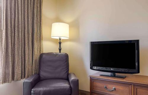 a room with a chair and a flat screen tv at Extended Stay America Select Suites - Dallas - Farmers Branch in Farmers Branch