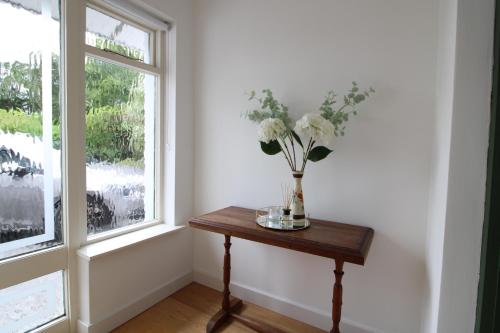 a vase of flowers on a table next to a window at THE VILLAGE HOUSE on Wild Atlantic Way CLARINBRIDGE VILLAGE in Galway