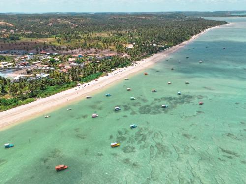 une vue aérienne d'une plage avec des bateaux dans l'eau dans l'établissement Lindo loft a poucos metros da Praia no Patacho!, à Porto de Pedras