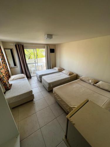 a room with three beds and a large window at Pousada Morada das Nações in Balneário Camboriú
