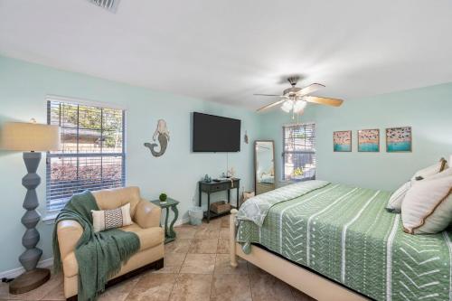 a bedroom with a bed and a tv and a chair at Beautiful Pet Friendly Home! Tropical Pool, Optional Golf Cart & Pool Heat, Minutes to Beach in Destin