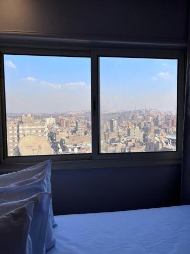 a bedroom with two windows with a view of a city at Heaven Hostel in Cairo