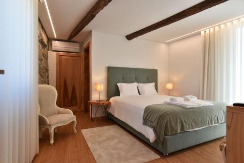 a bedroom with a large bed and a chair at Feel Discovery Casa da Pedra in Arouca