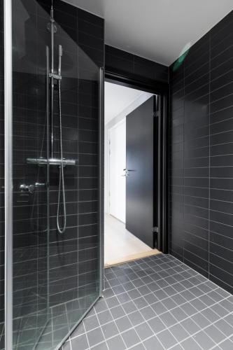 a bathroom with a shower with black tiles at Super Central Designer Penthouse at 19th floor with Amazing View! in Oslo