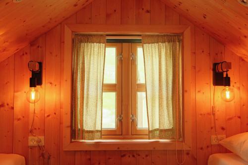 a bedroom with a window in a wooden wall at Múlafossur Cottages by famous waterfall in Gásadalur in Gásadalur