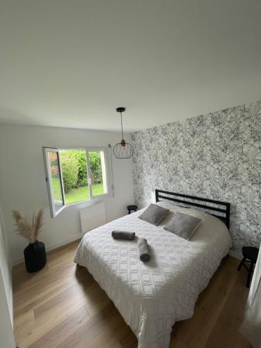 a bedroom with a bed with a white comforter and a window at Maison cosy avec jacuzzi in Néant-sur-Yvel