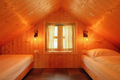 two beds in a room with a window at Múlafossur Cottages by famous waterfall in Gásadalur in Gásadalur