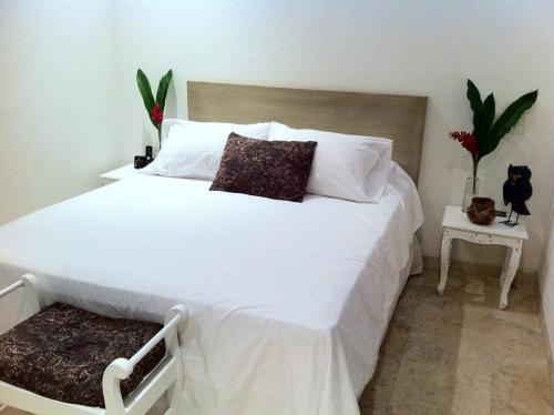 une chambre avec un grand lit avec des draps et des oreillers blancs dans l'établissement Charming 1BR apartment in the Heart of Cartagena's Old City, à Carthagène des Indes