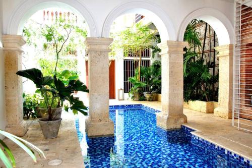 une piscine au milieu d'une maison avec des colonnes dans l'établissement Charming 1BR apartment in the Heart of Cartagena's Old City, à Carthagène des Indes