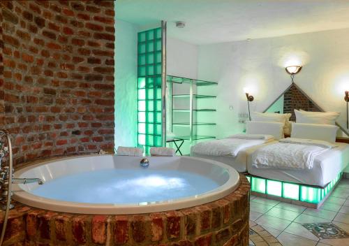 a large bathroom with a large tub and two beds at Hotel Land Gut Höhne in Mettmann