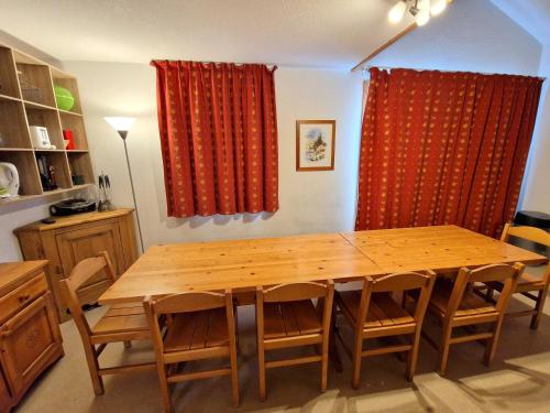 une table à manger en bois avec des chaises et des rideaux rouges dans l'établissement Joli duplex spacieux 10/12 personnes - FR-1-265-174, à Valfréjus