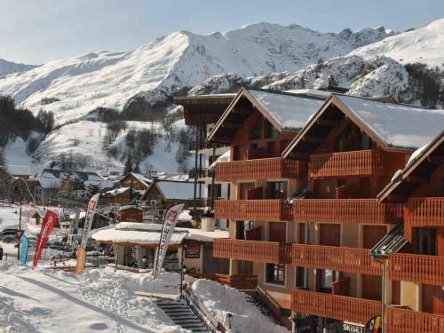 un lodge de ski avec des montagnes enneigées en arrière-plan dans l'établissement Charmant studio cabine pour 4 personnes, au centre de Valloire, à 100m des remontées mécaniques - FR-1-263-486, à Valloire