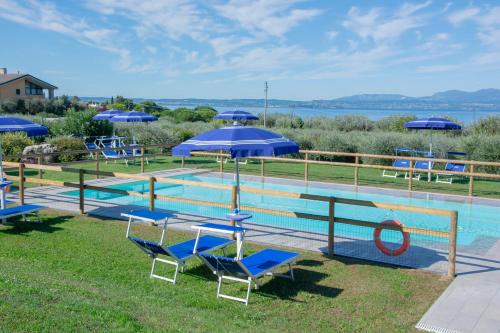 a group of chairs and umbrellas next to a pool at Agriturismo Il Giardino Degli Ulivi in Lazise