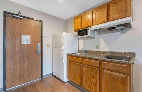 a kitchen with a white refrigerator and wooden cabinets at Extended Stay America Select Suites - Orlando - South in Orlando