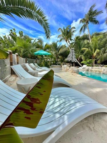 a surfboard and lounge chairs on the beach next to a pool at Bungalows Beach Key West - Azucar in Key West