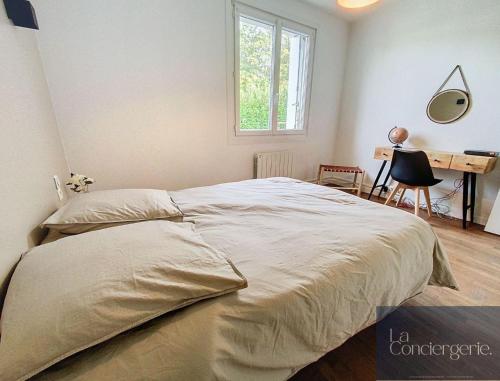 a bedroom with a bed and a desk and a window at Beausoleil - Futuroscope - LaConciergerie in Chasseneuil-du-Poitou