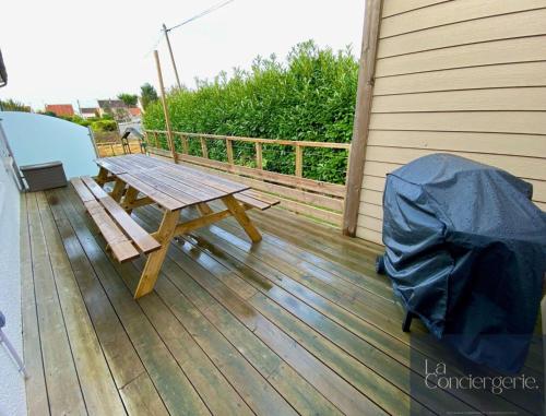 a wooden picnic table on the deck of a house at Beausoleil - Futuroscope - LaConciergerie in Chasseneuil-du-Poitou