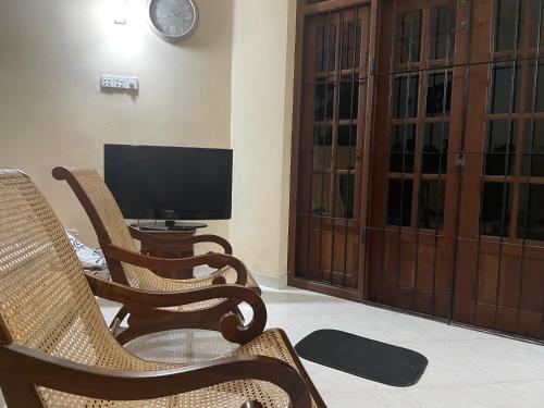 a living room with two chairs and a television at Marigold Negombo in Negombo