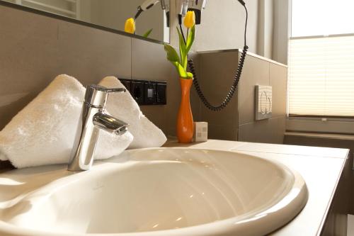 a bathroom with a sink and a vase with yellow flowers at Sylter Domizil in Wenningstedt