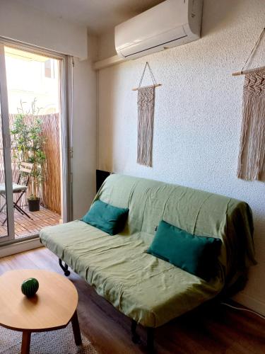 - un canapé vert dans une chambre avec fenêtre dans l'établissement Appartement Bambou, à Sète