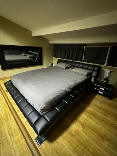 a large bed in a bedroom with a black leather bed frame at Villa Brussel in Dilbeek