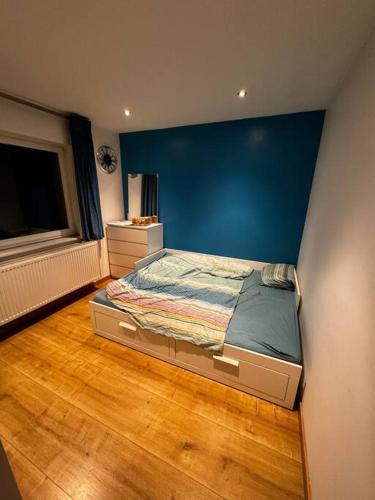 a bedroom with a bed with a blue wall at Villa Brussel in Dilbeek