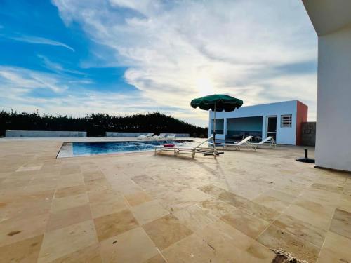 a patio with an umbrella and chairs and a pool at Riverside 3BR Farm - Pool & Stunning Views in Oulad Yakoub