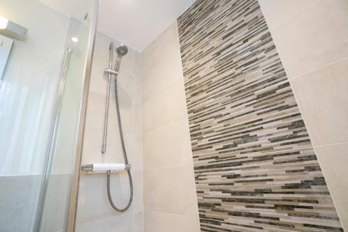 a bathroom with a shower with a stone wall at Marlborough House - Guest House in Oxford