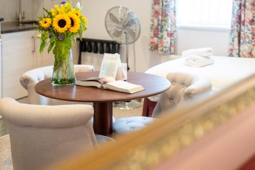 a table with a vase of flowers and a book at Marlborough House - Guest House in Oxford
