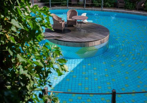 a swimming pool with two chairs and a table at Hotel Land Gut Höhne in Mettmann