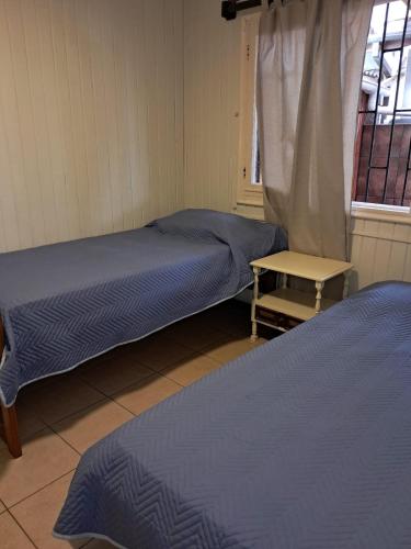 a room with two beds and a table and a window at Acogedora casa en la playa in El Quisco