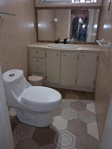 a bathroom with a white toilet and a sink at Acogedora casa en la playa in El Quisco