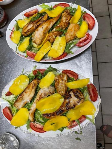 two plates of food with chicken and vegetables on a table at Wald Cafe in Simbach am Inn