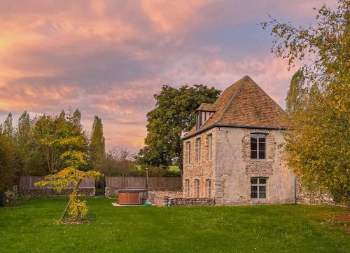 - un vieux bâtiment en pierre dans une cour avec un arbre dans l'établissement Le Fruitier, à Lommoye