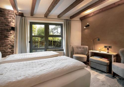 a bedroom with a bed and a desk and a window at Hotel Land Gut Höhne in Mettmann