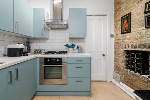 a kitchen with blue appliances and a brick wall at GuestReady - Lovely stay in the heart of London in London