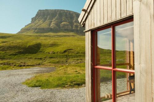 a window of a building with a mountain in the background at Múlafossur Cottages by famous waterfall in Gásadalur in Gásadalur