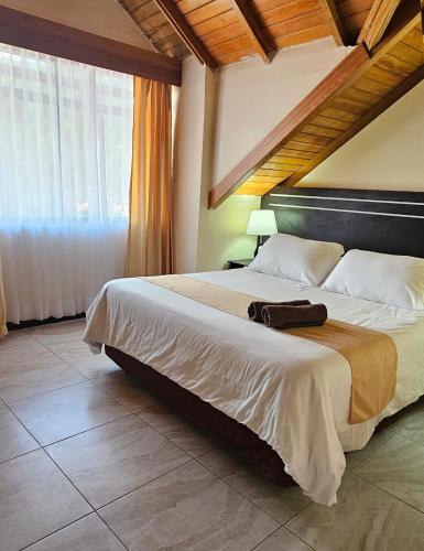 a bedroom with a large bed with a large window at Hotel Tungurahua in Baños