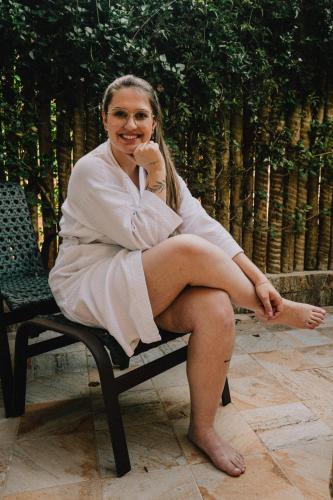 a woman in a robe sitting on a bench at LA PIANTA - Uma experiência na Villa de Monte Verde in Monte Verde