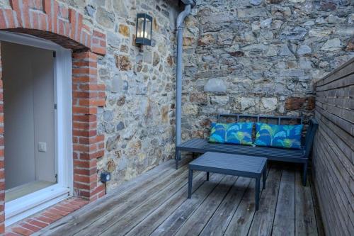 un banco sentado en una terraza de madera junto a una pared de piedra en Ti Gwer - vue mer - wifi, en Crozon
