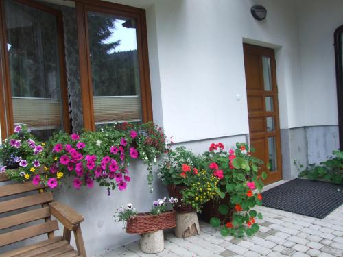 a porch with flowers and a bench in front of a building at Pokoje i apartamenty pod Jaworzyną w Koninkach in Koninki