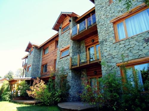 a large stone building with wooden balconies on it at Hosteria Patagon in Villa La Angostura