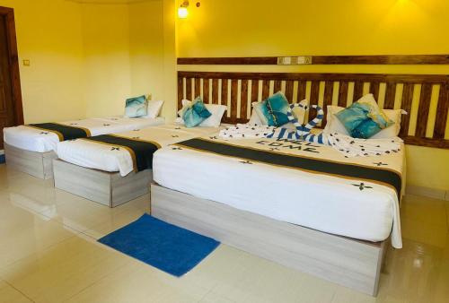 two large beds in a room with yellow walls at Sorenzo Maldives in Thoddoo