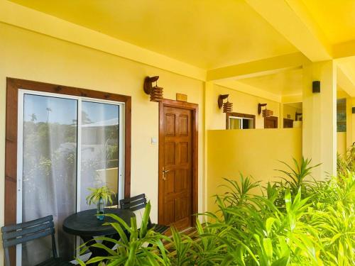 a yellow house with a table and a door at Sorenzo Maldives in Thoddoo