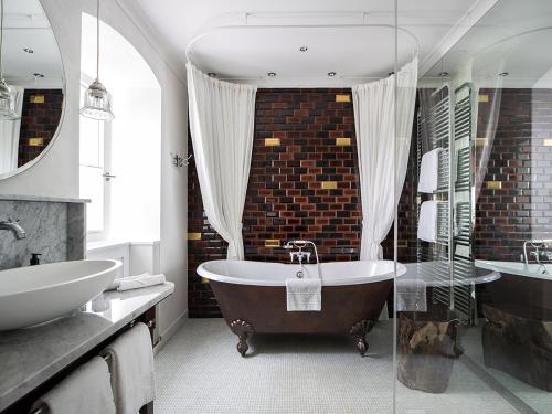 a bathroom with a large tub and a sink and a tub at LA MAISON hotel & spa in Saarlouis